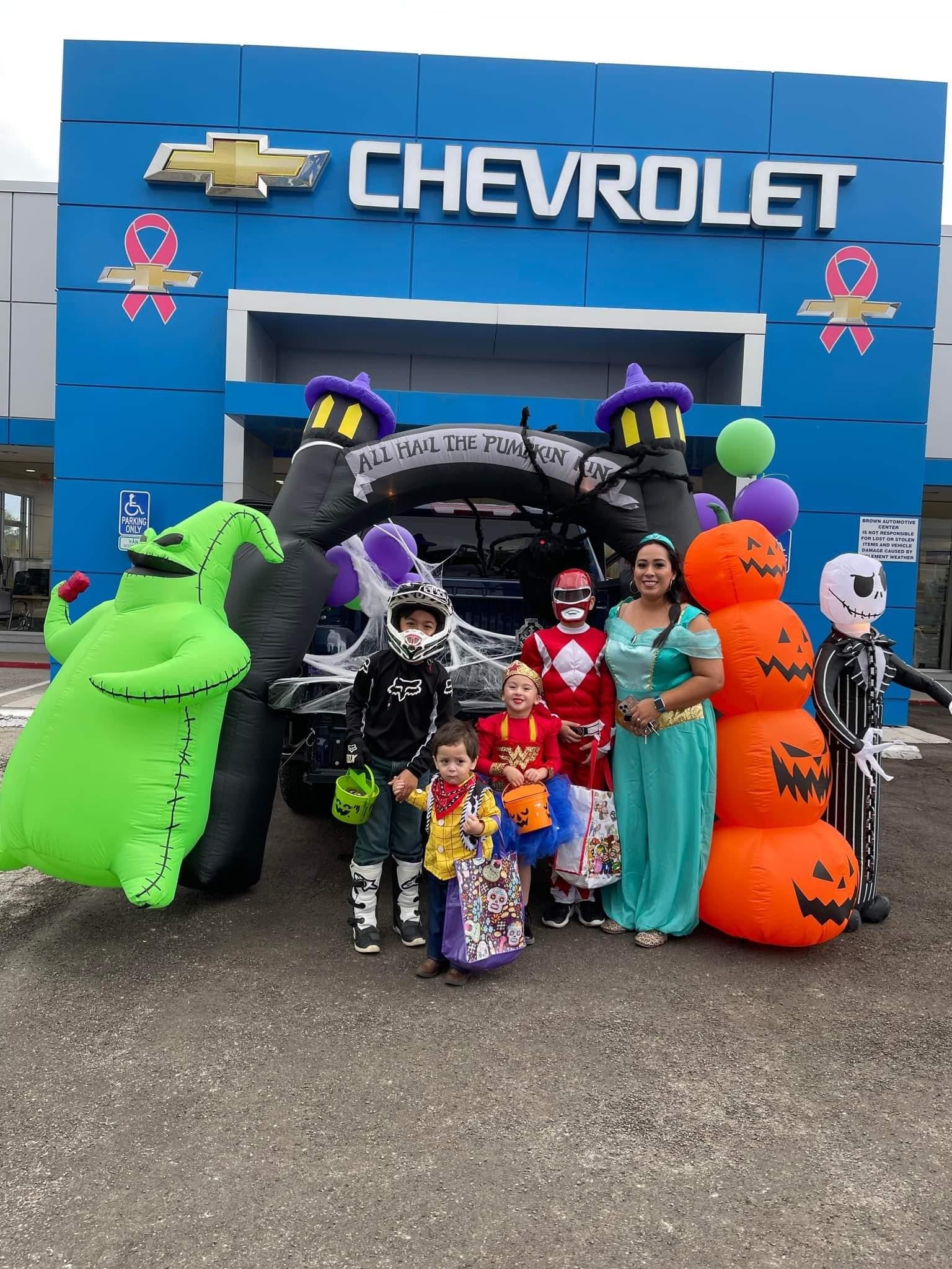 Kids and adults in Halloween costumes posing at decorated Chevrolet trunk-or-treat setup