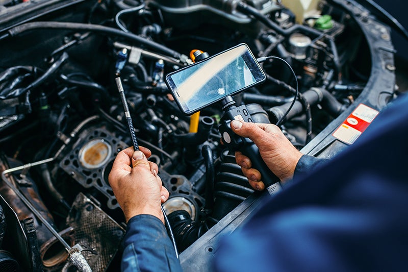 Technician diagnosing car engine with connected device